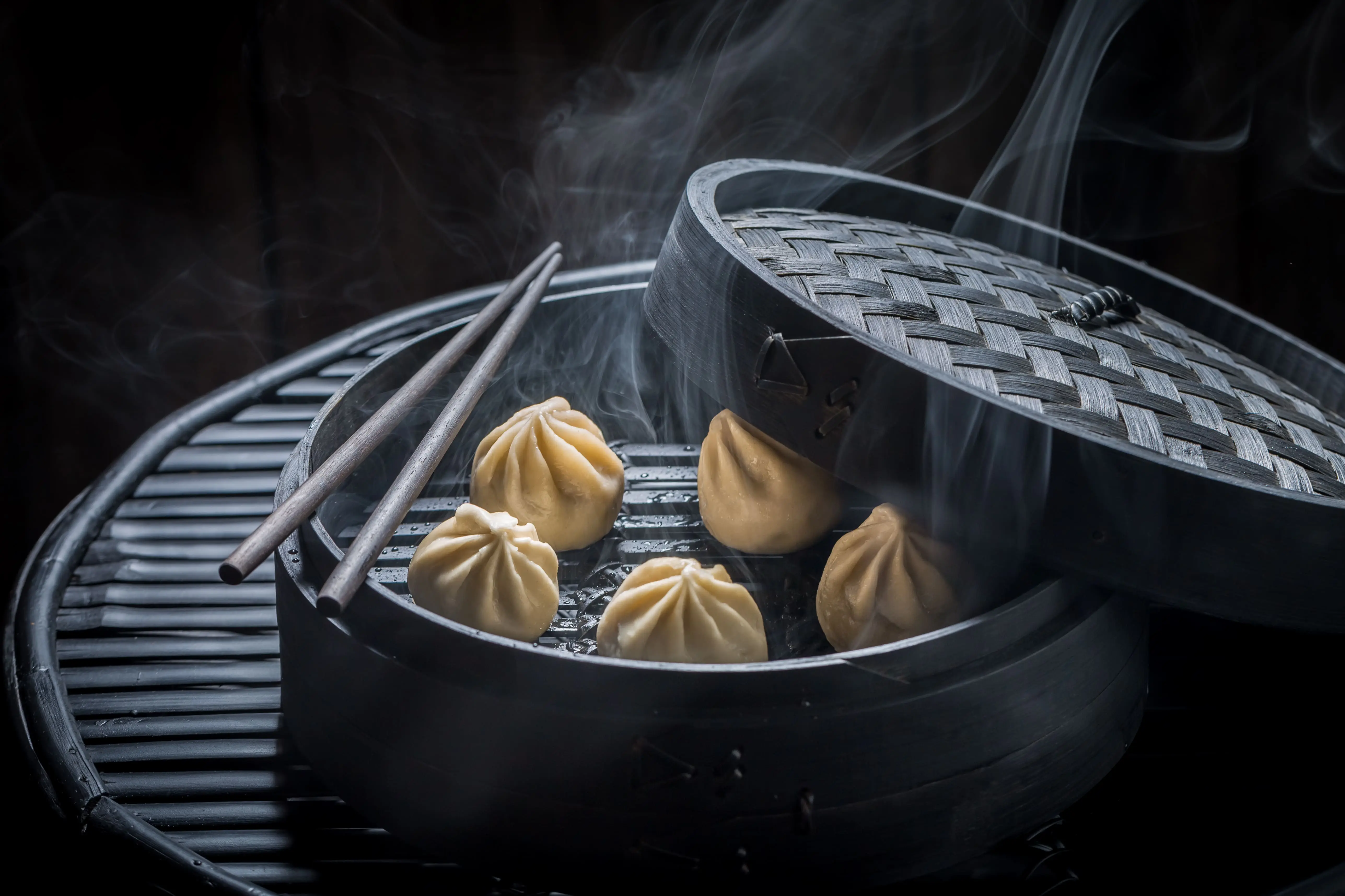 Steamed dumplings served in a wooden bowl with chopsticks